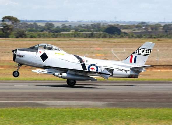 Vintage fighter jet taking off from a runway.