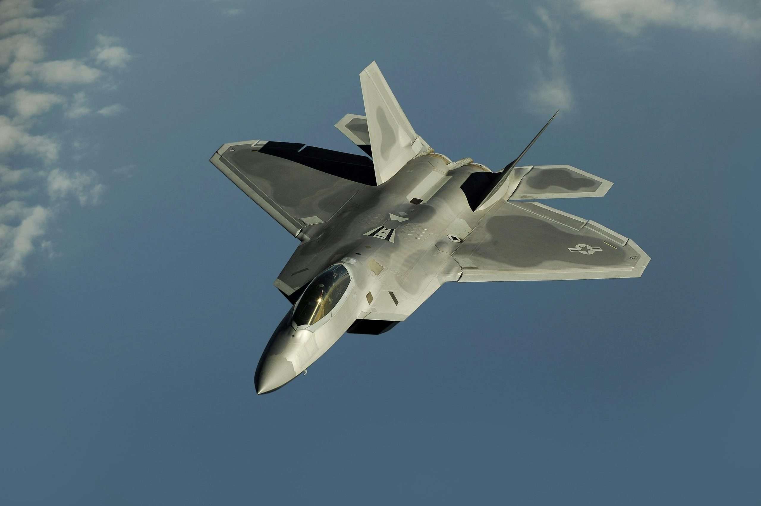 Stealth fighter jet soaring through a clear blue sky.