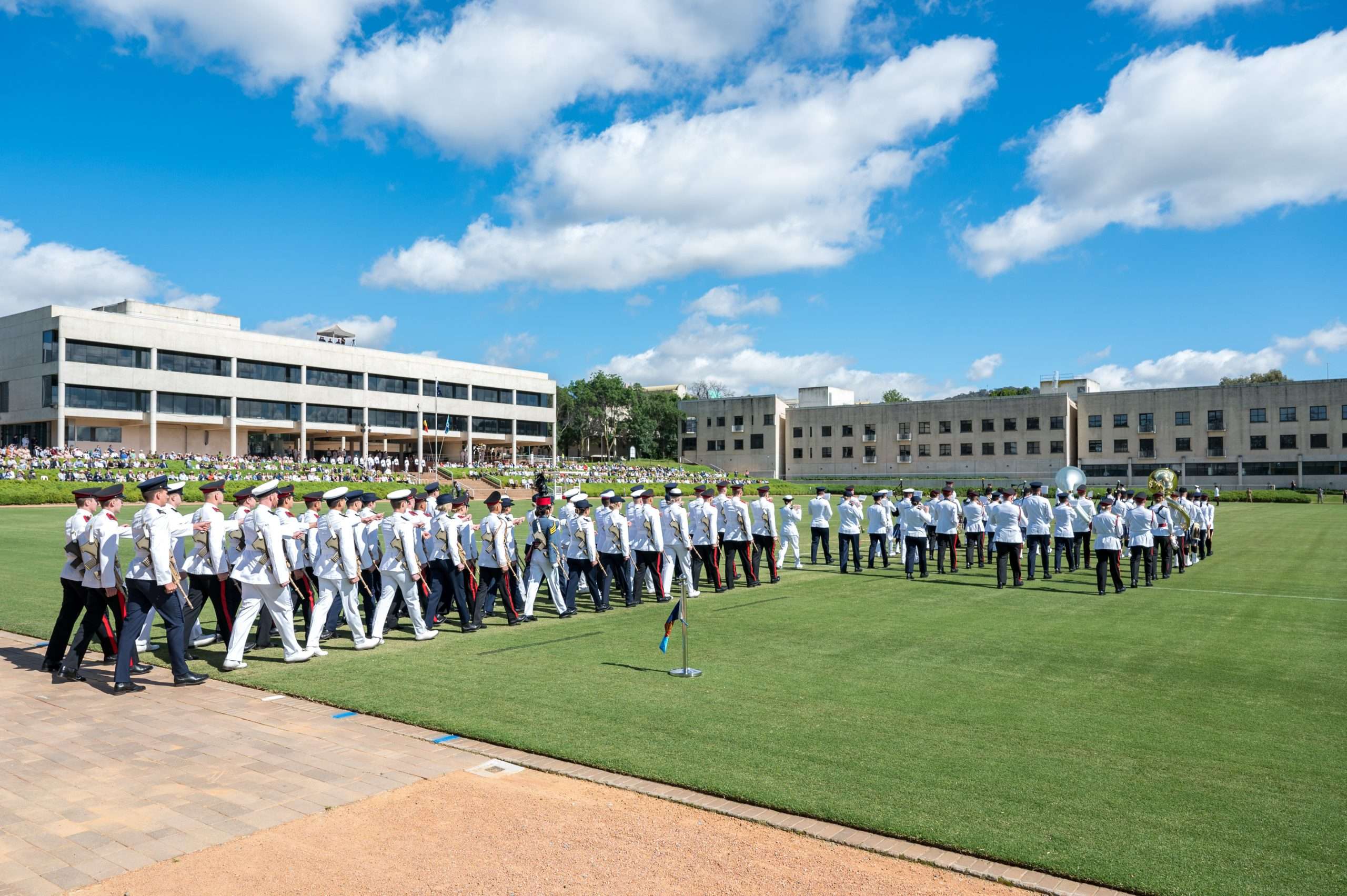 A military parade and band performing on a large field.