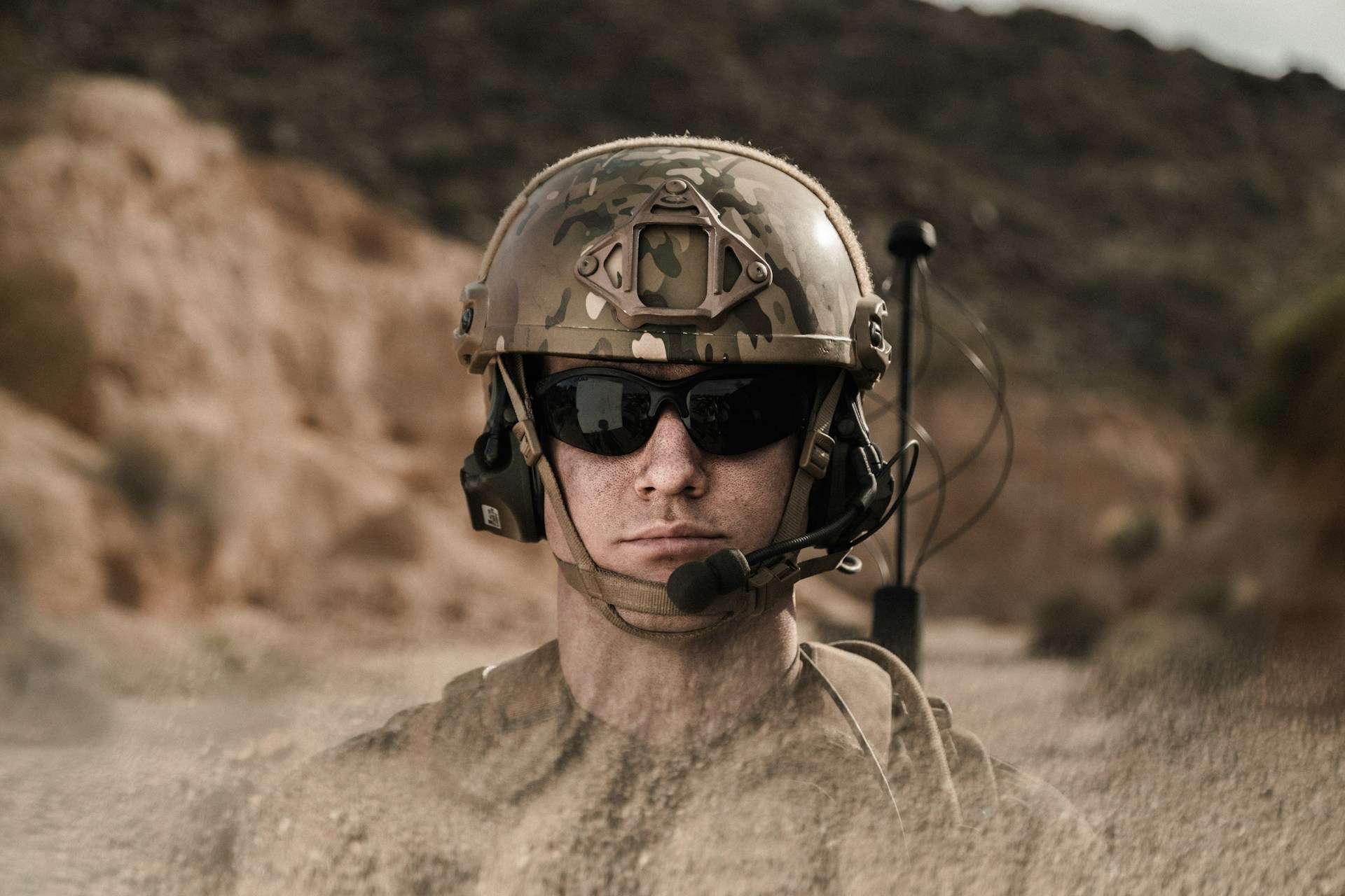 A tactical operator wearing a camouflage helmet and sunglasses.