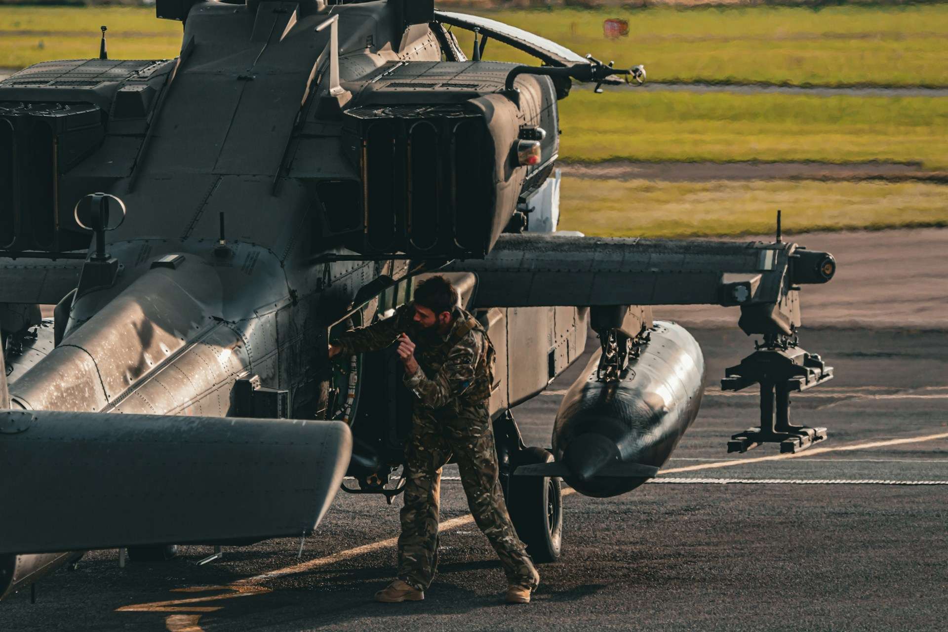 A soldier inspecting a military helicopter on the tarmac.
