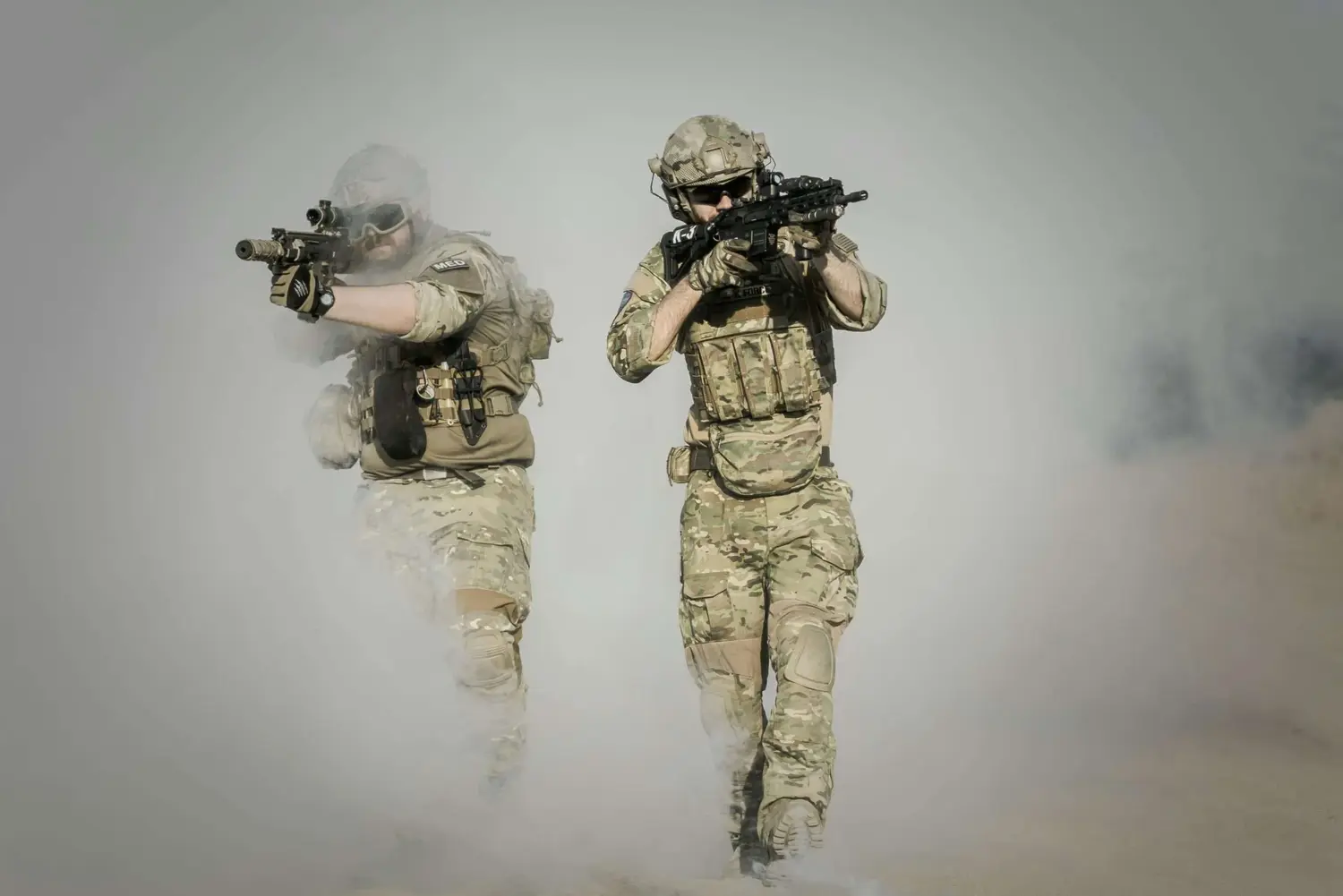 Two tactical operators advancing through smoke.