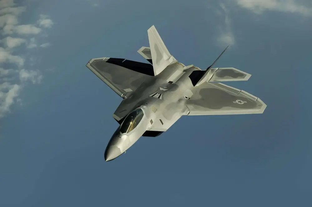 Stealth fighter jet soaring through a clear blue sky.