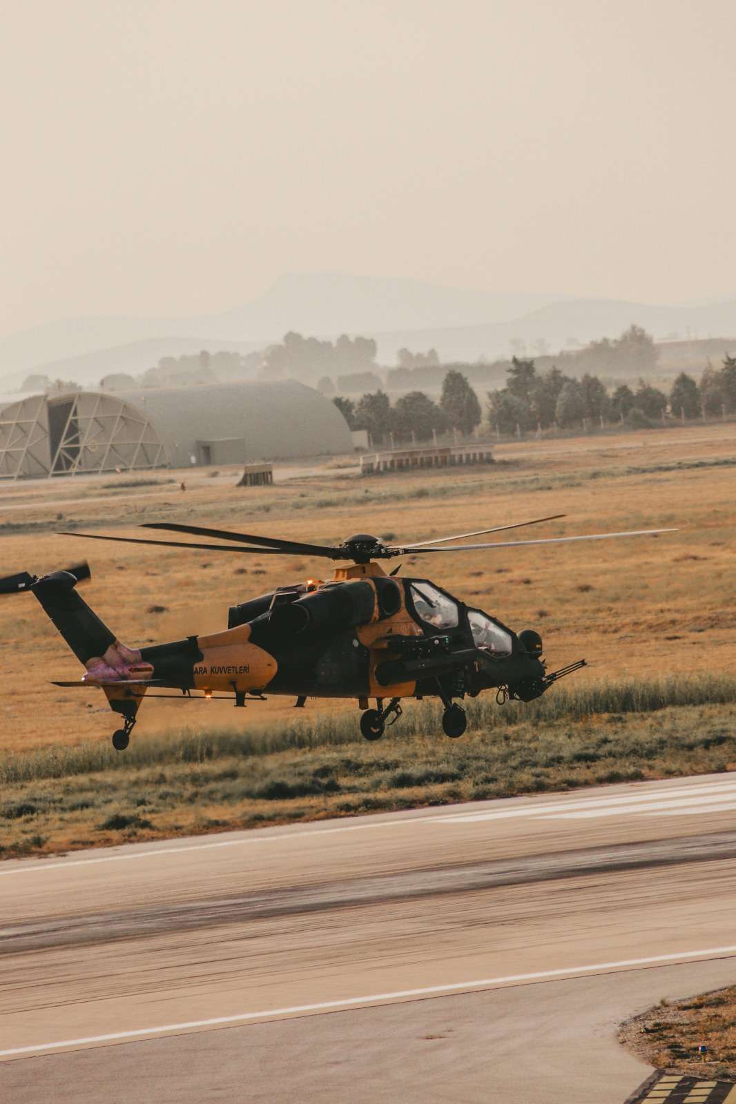 A military helicopter taking off from a runway.