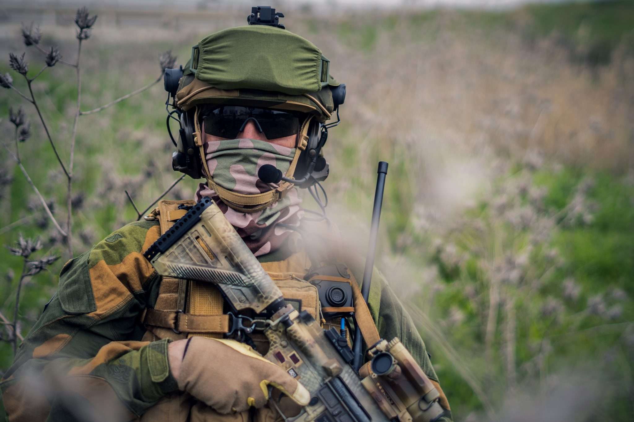 A soldier in tactical gear holding a rifle.