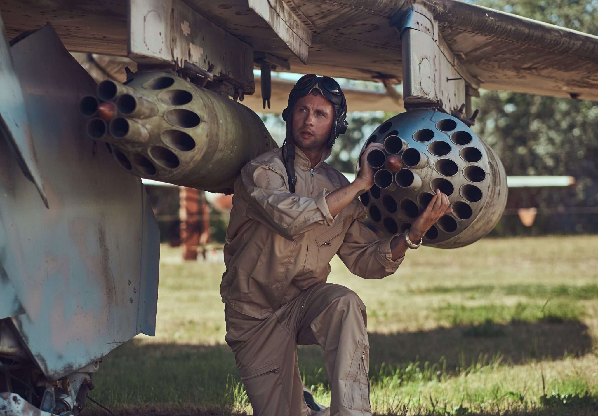 Pilot or technician inspecting rocket pods mounted under the wing of an aircraft.