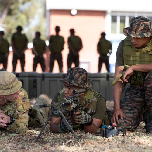 Military personnel in uniform conducting tactical training outdoors.