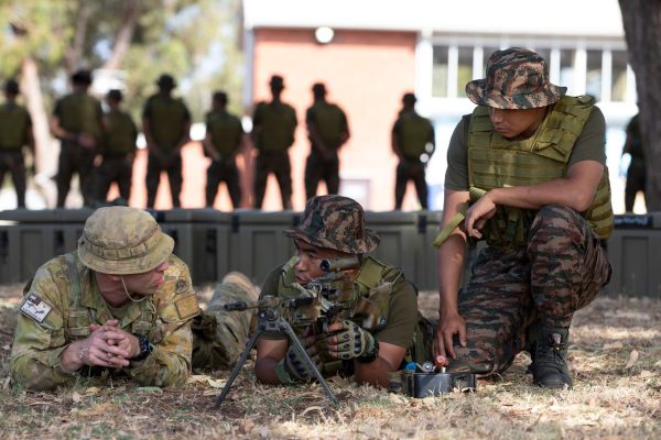 Military personnel in uniform conducting tactical training outdoors.