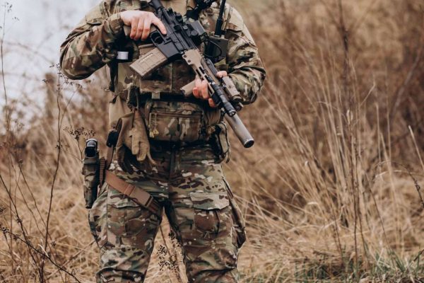 Army soldiers fighting with guns and defending their country Soldier in camouflage gear holding a tactical rifle outdoors.