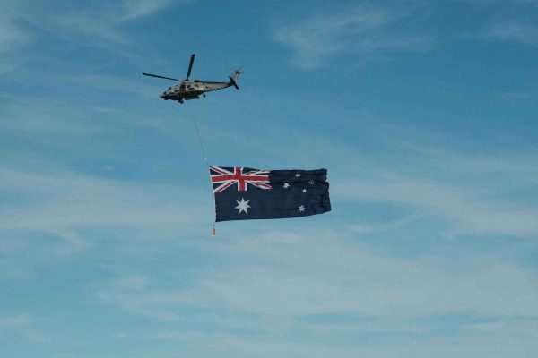 dominic-kurniawan-suryaputra-d5X5rXmHKJk-unsplash A helicopter flying in the sky while carrying a large Australian flag.